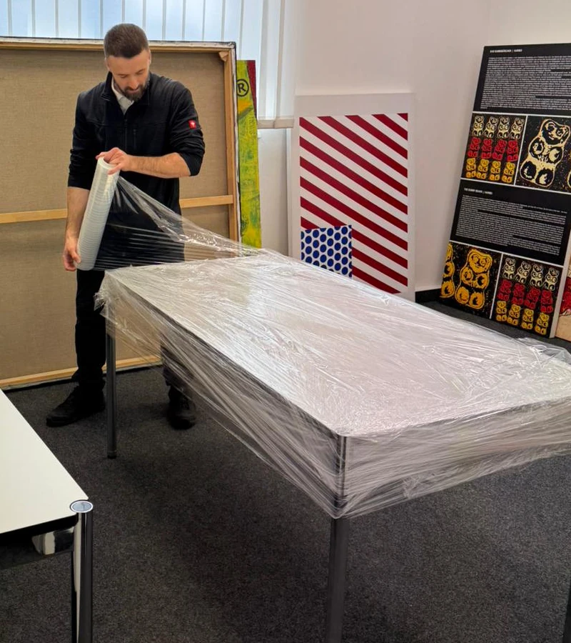 Umzugshelfer verpackt Tisch mit Stretchfolie für den Umzug